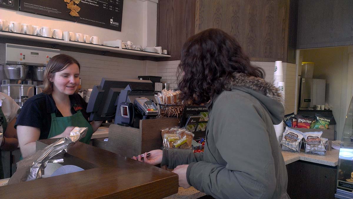 Customer in coffee shop paying using a smartphone